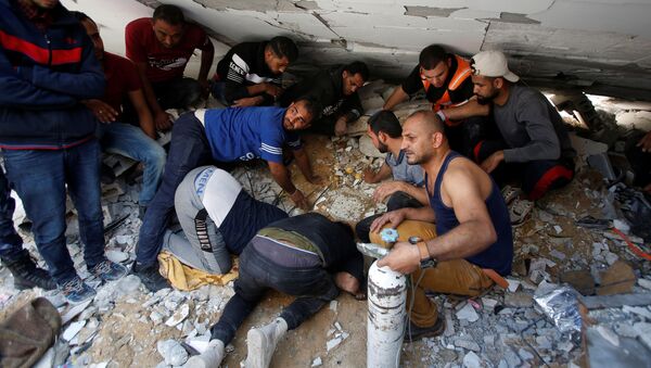 Palestinos atuam para retirar pessoas de escombros de prédio bombardeado por Israel na Faixa de Gaza - Sputnik Brasil