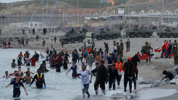Cidadãos marroquinos caminham na água enquanto legionários espanhóis patrulham a área perto da cerca em uma praia em El Tarajal,  em Ceuta, Espanha, 18 de maio de 2021 - Sputnik Brasil