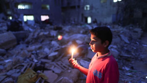 Menino segura vela no local onde uma casa foi destruída por ataques aéreos israelenses, em Gaza em 23 de maio de 2021 - Sputnik Brasil