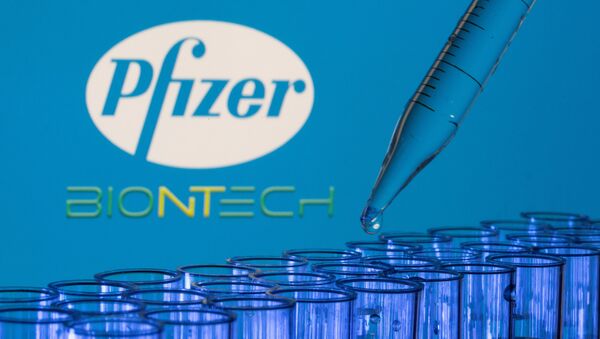 Tubos de ensaio são vistos à frente dos logotipos da Pfizer e da Biontech em foto de 21 de maio de 2021 - Sputnik Brasil