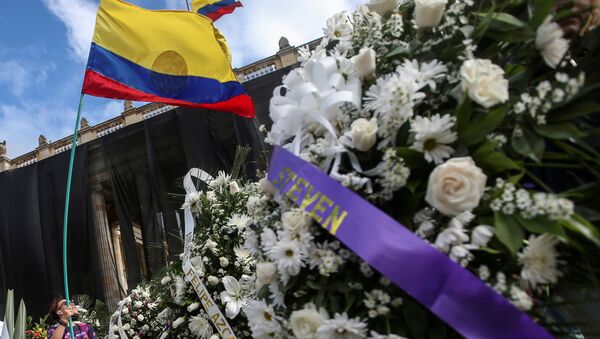 Manifestante ergue bandeira colombiana perto de coroas de flores com nomes de pessoas que morreram em protestos recentes, em Bogotá, Colômbia, 24 de maio de 2021 - Sputnik Brasil
