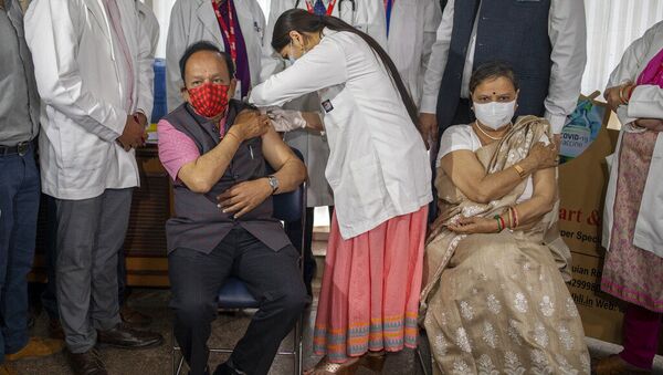 O ministro da Saúde da Índia, Harsh Vardhan, é administrado com a vacina COVAXIN, desenvolvida pela empresa indiana Bharat Biotech, com sua esposa Nutan Goel sentada ao lado dele após receber sua injeção em um hospital privado em Nova Deli, Índia. Foto de arquivo - Sputnik Brasil