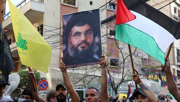 Um manifestante segura uma foto do líder libanês do Hezbollah Sayyed Hassan Nasrallah, durante um protesto para expressar solidariedade ao povo palestino, nos subúrbios de Beirute, Líbano, 17 de maio de 2021 - Sputnik Brasil