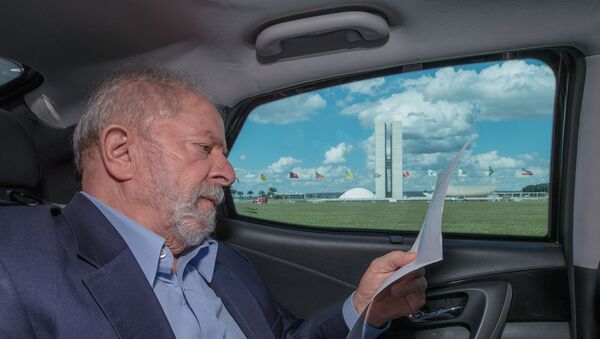 Ex-presidente Luiz Inácio Lula da Silva lê dentro de carro passando em frente ao Congresso Nacional, em Brasília - Sputnik Brasil