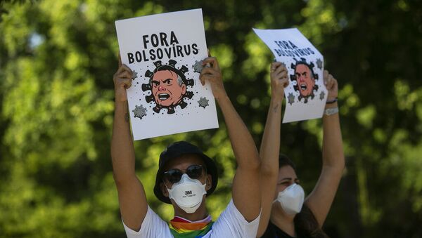 Manifestantes usando máscaras seguram cartazes retratando o presidente Jair Bolsonaro como um vírus durante protesto contra a resposta do governo federal no combate à COVID-19, no Rio de Janeiro, Brasil, sábado, 29 de maio de 2021 - Sputnik Brasil
