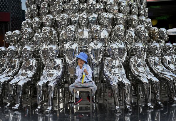 Menino sentado entre várias esculturas expostas em um centro comercial de Pequim, na China 
 - Sputnik Brasil