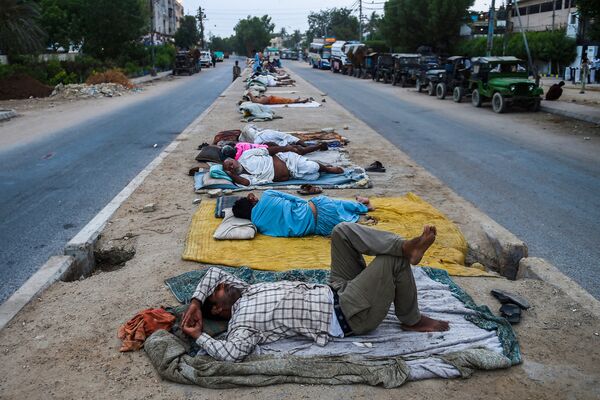Trabalhadores dormindo na faixa divisória em rodovia da cidade portuária de Karachi, Paquistão - Sputnik Brasil