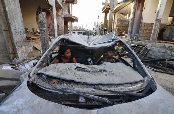 Crianças palestinas brincam dentro de carro destruído durante conflito entre o Hamas e Israel, em Beit Hanun, Faixa de Gaza, 7 de junho de 2021 - Sputnik Brasil