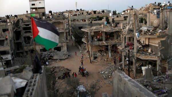 Bandeira palestina voa em meio às ruínas de casas, destruídas por ataques aéreos israelenses durante conflito israelo-palestino na Faixa de Gaza, 25 de maio de 2021 - Sputnik Brasil