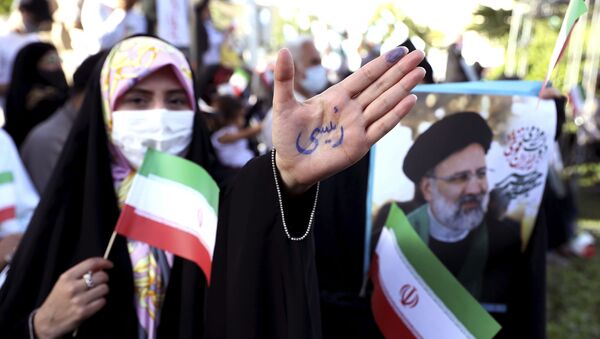 Apoiadora do candidato a presidente Ebrahim Raisi mostra inscrição em persa de seu nome, Raisi, durante manifestação em Teerã, Irã, antes da eleição presidencial, 16 de junho de 2021 - Sputnik Brasil