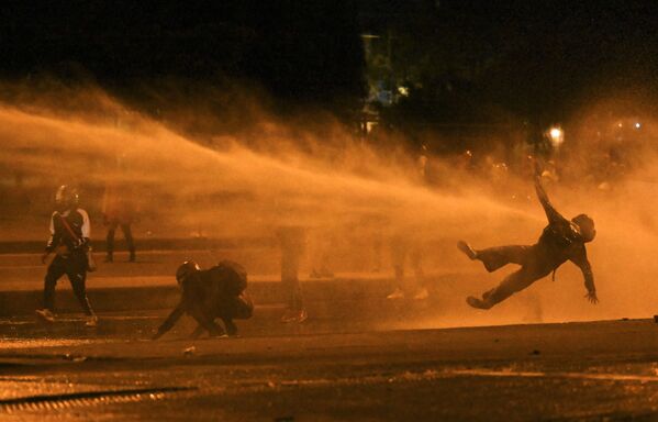 Manifestante cai após ser atingido por canhão de água durante confrontos com a polícia de choque, em meio aos protestos contra o governo do presidente colombiano Iván Duque, em Bogotá, Colômbia, 12 de junho de 2021 - Sputnik Brasil