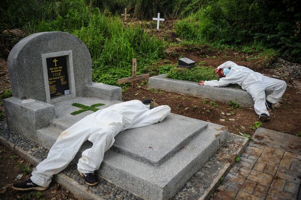 Trabalhadores com fatos protetores descansam após enterrar vítima do SARS-CoV-2 em Bandung, província de Java Ocidental, Indonésia - Sputnik Brasil