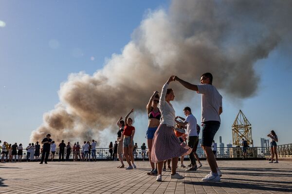 Pessoas dançam samba enquanto fumaça sobe de depósito pirotécnico em chamas em Moscou, Rússia, 19 de junho de 2021 - Sputnik Brasil