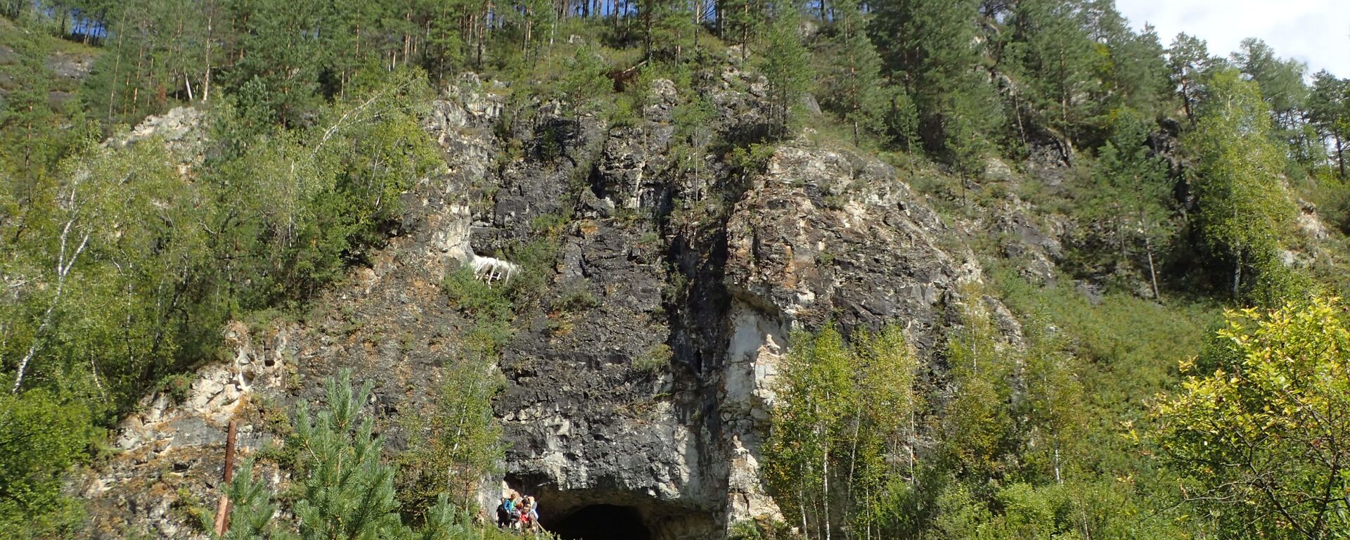 Exterior da caverna Denisova, na Sibéria, Rússia, onde cientistas da Austrália, Alemanha e Rússia encontraram uma história ocupacional de diferentes grupos humanos - Sputnik Brasil, 1920, 30.11.2021