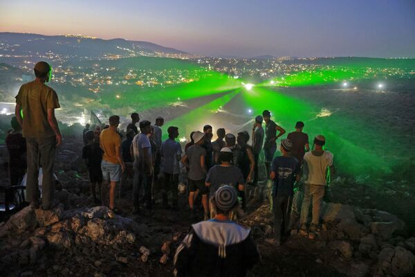 Colonos e apoiadores israelenses no recém-criado posto avançado de Eviatar observam manifestantes palestinos apontando raios laser em sua direção a partir da aldeia vizinha de Beita, perto da cidade palestina de Nablus, Cisjordânia ocupada, 28 de junho de 2021 - Sputnik Brasil