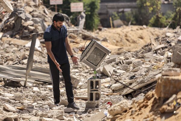 Artista de performance palestino Mohammed al-Shenbari ajusta uma televisão em cima de garrafa colocada em escombros demonstrando sua habilidade em equilibrar objetos
 - Sputnik Brasil