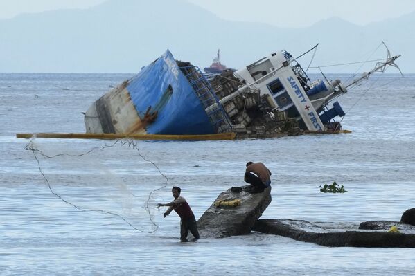 Pescador lança rede de pesca perto de um navio meio submerso na baía de Manila, Filipinas
 - Sputnik Brasil