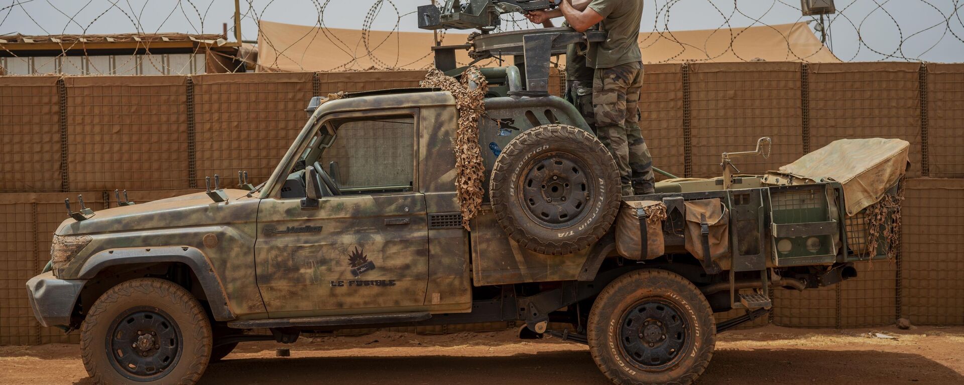 Soldados da força francesa da operação Barkhane montam uma metralhadora em uma picape camuflada enquanto trabalhadores do Mali passam antes de partir em uma missão de sua base em Gao, Mali, 7 de junho de 2021 - Sputnik Brasil, 1920, 25.01.2022