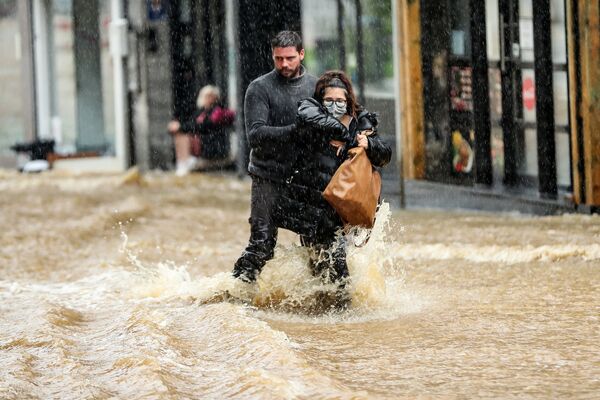 Homem ajuda mulher a atravessar rua inundada na cidade de Spa, na Bélgica
 - Sputnik Brasil
