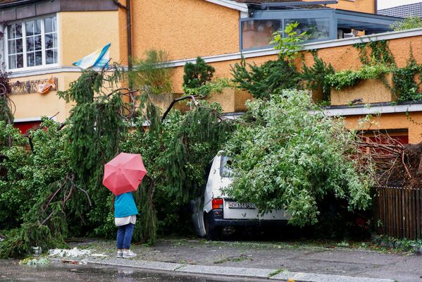 Mulher diante de van danificada por queda de árvore durante tempestade e chuvas fortes em Zurique, Suíça - Sputnik Brasil