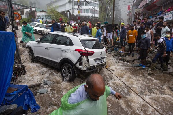 Pessoas tentam recuperar carro danificado nas inundações provocadas pelas chuvas torrenciais na Índia  
 - Sputnik Brasil
