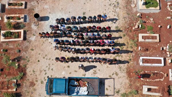 Vista aérea mostra enlutados orando pelos corpos de três crianças, que foram mortas em um bombardeio na província de Idlib, no noroeste da Síria - Sputnik Brasil