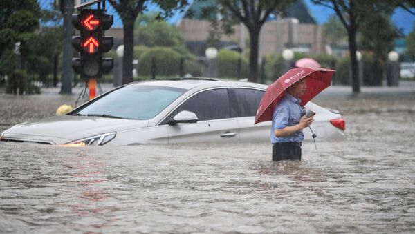 Homem ao lado de carro sumerso em Zhengzhou, província de Henan, China, 20 de julho de 2021 - Sputnik Brasil