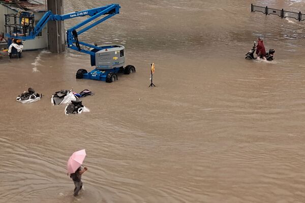 Pessoas passam por rua inundada após as chuvas torrenciais que atingiram a cidade de Zhengzhou, China, 20 de julho de 2021 - Sputnik Brasil