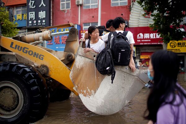 Pessoas viajando em uma carregadeira devido às estradas inundadas após chuvas fortes em Zhengzhou, província de Henan, China, 22 de julho de 2021 - Sputnik Brasil
