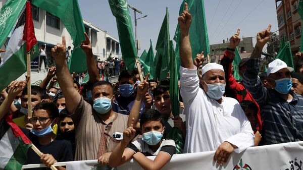 Apoiadores do Hamas usando máscaras acenam bandeiras islâmicas verdes enquanto entoam slogans durante comício em solidariedade aos companheiros palestinos em Jerusalém e contra a decisão do presidente palestino Mahmoud Abbas de adiar as eleições palestinas. Foto de arquivo - Sputnik Brasil