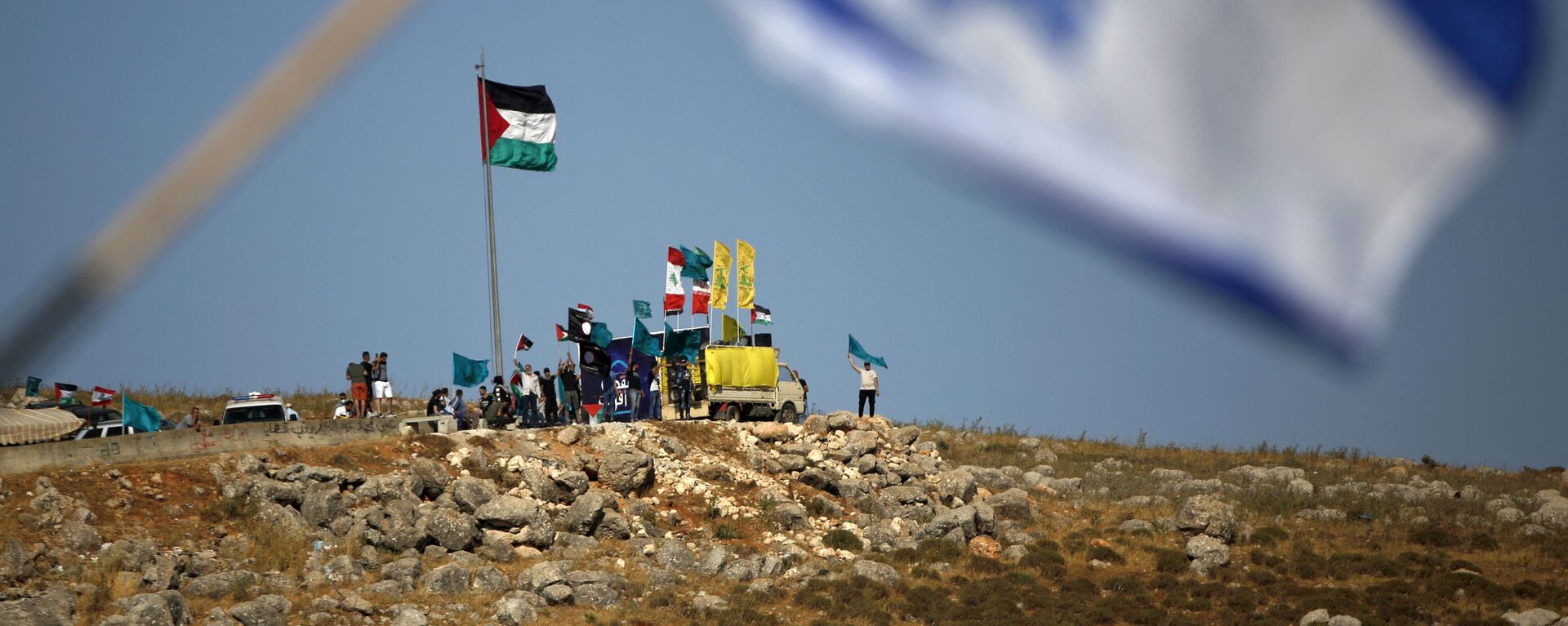 Na cidade de Metula, no norte de Israel, perto da fronteira com o Líbano, pessoas hasteiam bandeiras do Hezbollah, Líbano e Palestina durante manifestação em solidariedade aos palestinos, nos arredores da aldeia do sul do Líbano de Kfarkila. Foto de arquivo - Sputnik Brasil, 1920, 28.06.2022