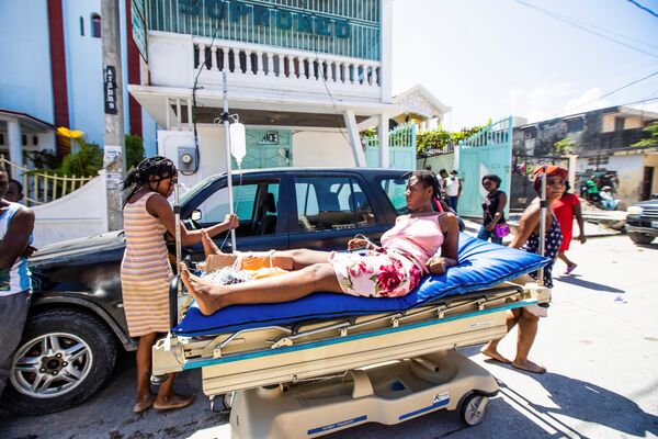 Pessoas transportam uma mulher ferida que sobreviveu à mais recente catástrofe natural no Haiti, 14 de agosto de 2021 - Sputnik Brasil