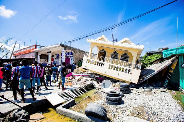Pessoas param em frente de uma casa destruída pelo terremoto de magnitude 7,2, 14 de agosto de 2021 - Sputnik Brasil