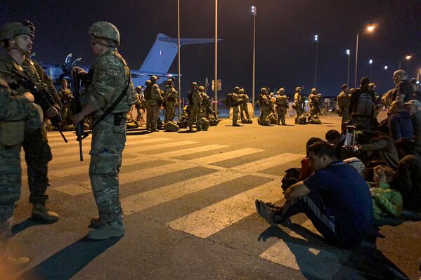 Soldados da França montam guarda enquanto cidadãos franceses e seus companheiros afegãos esperam para embarcar em um avião de transporte militar no aeroporto de Cabul, Afeganistão, 17 de agosto de 2021 - Sputnik Brasil