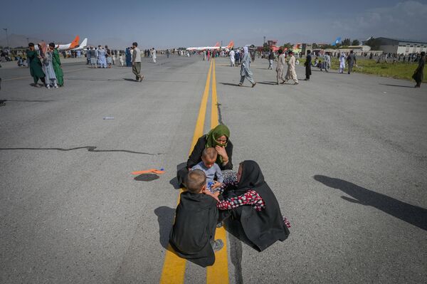 Afegãos sentados na pista esperando sair do país, Cabul, Afeganistão, 16 de agosto de 2021 - Sputnik Brasil