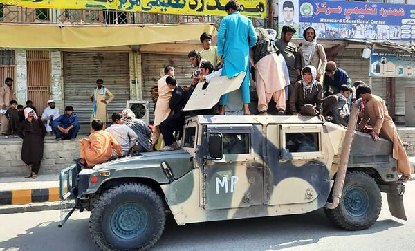 Militantes do Talibã (organização terrorista proibida na Rússia e em vários outros países) e residentes locais sentados em um veículo militar do Exército Nacional Afegão, na província de Laghman, 15 de agosto de 2021 - Sputnik Brasil