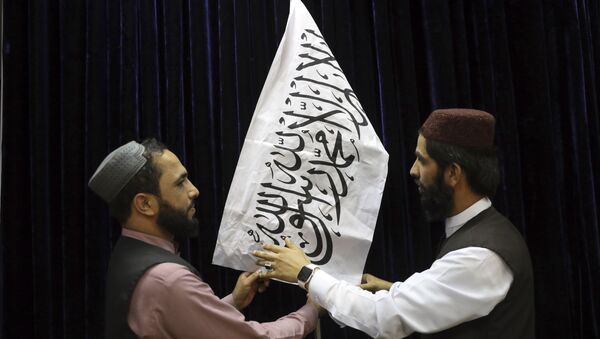 Talibãs arranjam a bandeira do movimento antes da primeira coletiva de imprensa do porta-voz do Talibã, Zabihullah Mujahid, Cabul, Afeganistão, 17 de agosto de 2021 - Sputnik Brasil