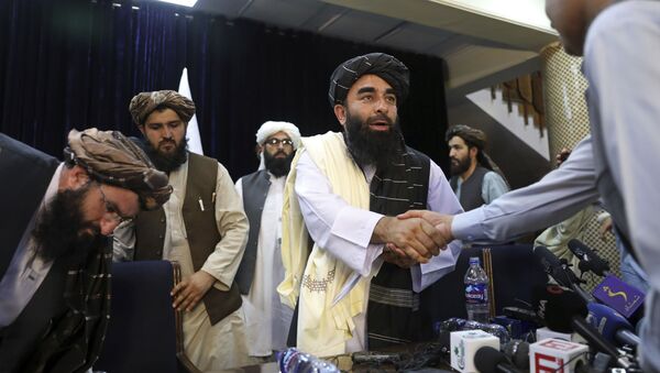 O porta-voz do Taleban, Zabihullah Mujahid, aperta a mão de um jornalista após sua primeira entrevista coletiva, em Cabul, Afeganistão, terça-feira, 17 de agosto de 2021 - Sputnik Brasil