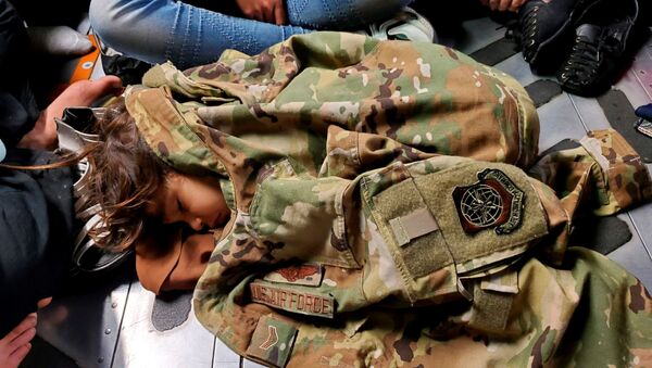 Criança afegã dorme no avião de transporte C-17 Globemaster III da Força Aérea dos EUA, coberta com uniforme do piloto Nicolas Baron, durante o voo de evacuação de Cabul, Afeganistão, 18 de agosto de 2021 - Sputnik Brasil
