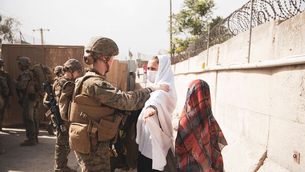 A U.S. Marine checks two civilians during processing through an Evacuee Control Checkpoint (ECC) during an evacuation at Hamid Karzai International Airport, Kabul, Afghanistan August 18, 2021. - Sputnik Brasil