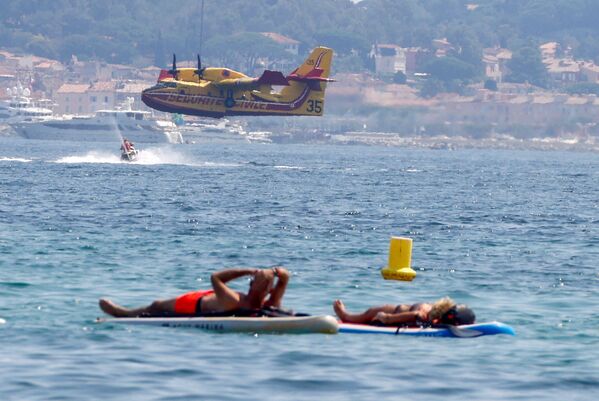 Pessoas descansam enquanto uma aeronave Canadair coleta água para combater um incêndio, França, 17 de agosto de 2021 - Sputnik Brasil