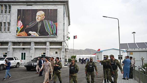 Pessoal de segurança passa ao lado de poster do ex-presidente afegão Hamid Karzai no aeroporto de Cabul em seu nome, 16 de julho de 2021 - Sputnik Brasil
