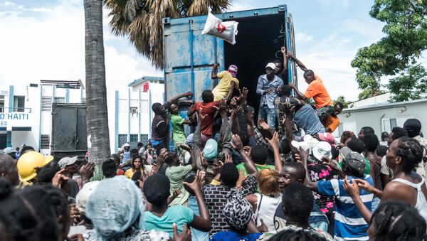 Homem joga saco de arroz para multidão durante distribuição de alimentos e água entre vítimas do terremoto em Les Cayes, Haiti - Sputnik Brasil
