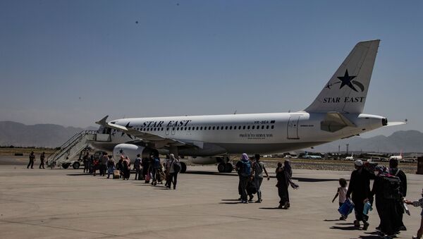 Evacuados são escoltados até uma aeronave durante uma evacuação no Aeroporto Internacional Hamid Karzai, Cabul, Afeganistão, 25 de agosto de 2021 - Sputnik Brasil