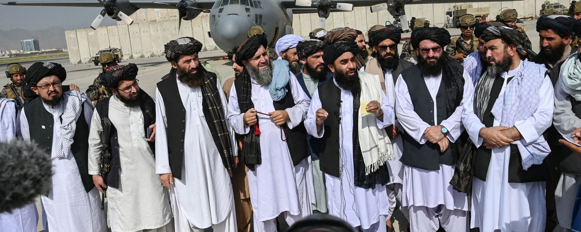 Porta-voz do Talibã, Zabihullah Mujahid (no centro com xaile), faz anúncio no aeroporto de Cabul após a saída das tropas americanas, 31 de agosto de 2021 - Sputnik Brasil, 1920, 19.02.2023