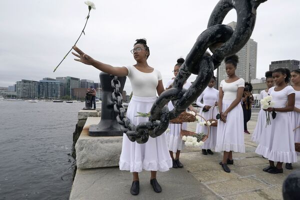Membro da trupe Girlz of Imani do Centro de Artes Culturais OrigiNation joga cravos na baía de Boston durante a cerimônia de reconhecimento da escravidão em Boston. - Sputnik Brasil