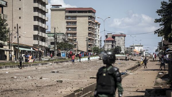 A Police officer looks on at protesters, as they continue to throw stones and block roads during mass protests after preliminary results were released in Conakry on October 23, 2020. - Sputnik Brasil