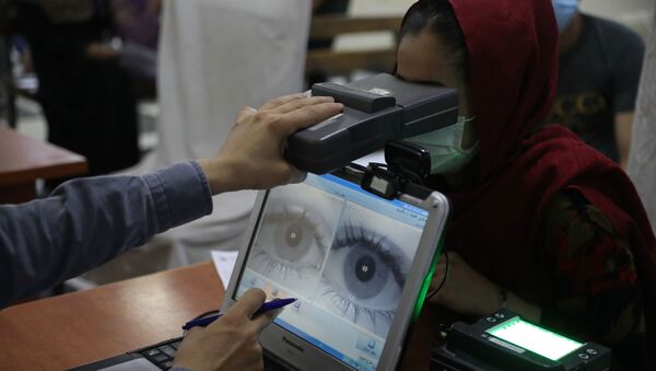Um funcionário examina os olhos de uma mulher em busca de dados biométricos necessários para solicitar um passaporte, no escritório de passaportes em Cabul, Afeganistão, 30 de junho de 2021 - Sputnik Brasil