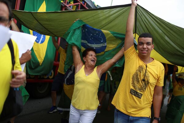 Pessoas participantes da marcha pelo Dia da Independência seguram bandeira do Brasil, em 7 de setembro de 2021. - Sputnik Brasil