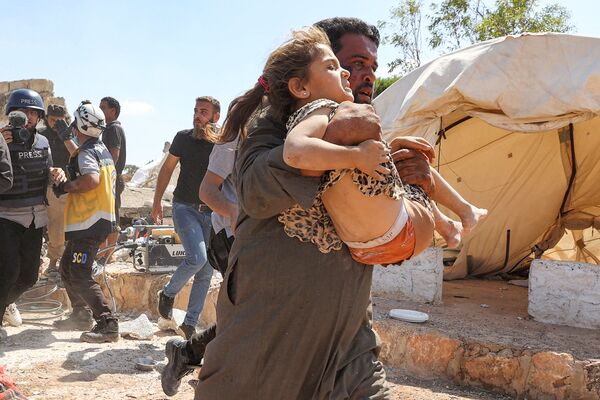 Homem carrega garota, ferida durante bombardeio de campo de refugiados no norte da Síria, 7 de setembro de 2021. - Sputnik Brasil